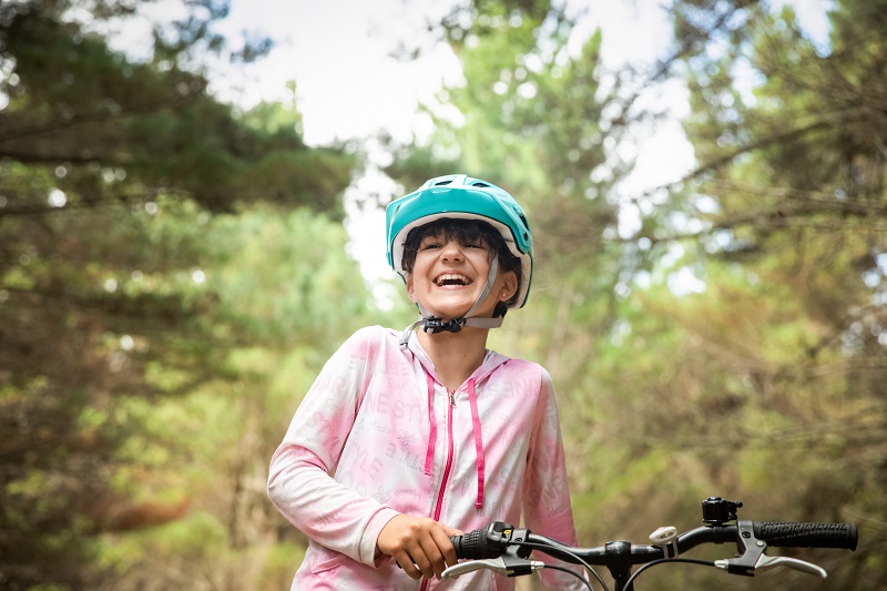 Young girl in a helmet riding a bike in a forest